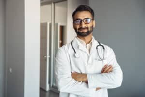Portrait of male doctor in white coat and stethoscope standing in clinic hall